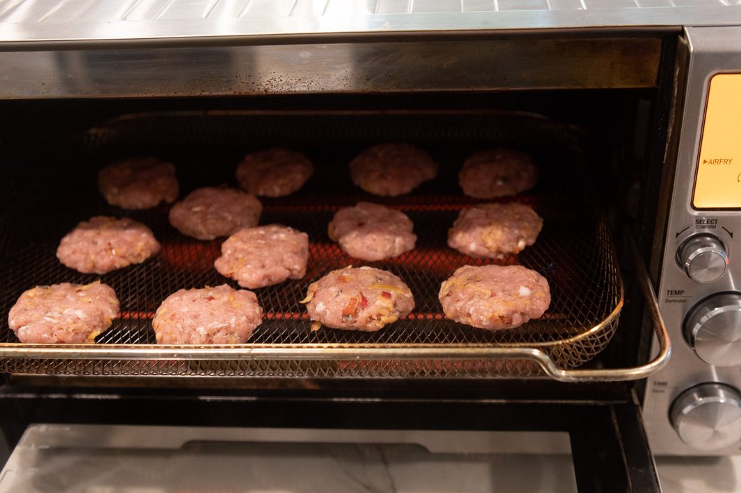 raw pork sausage patties placed in an air fryer ready to cook