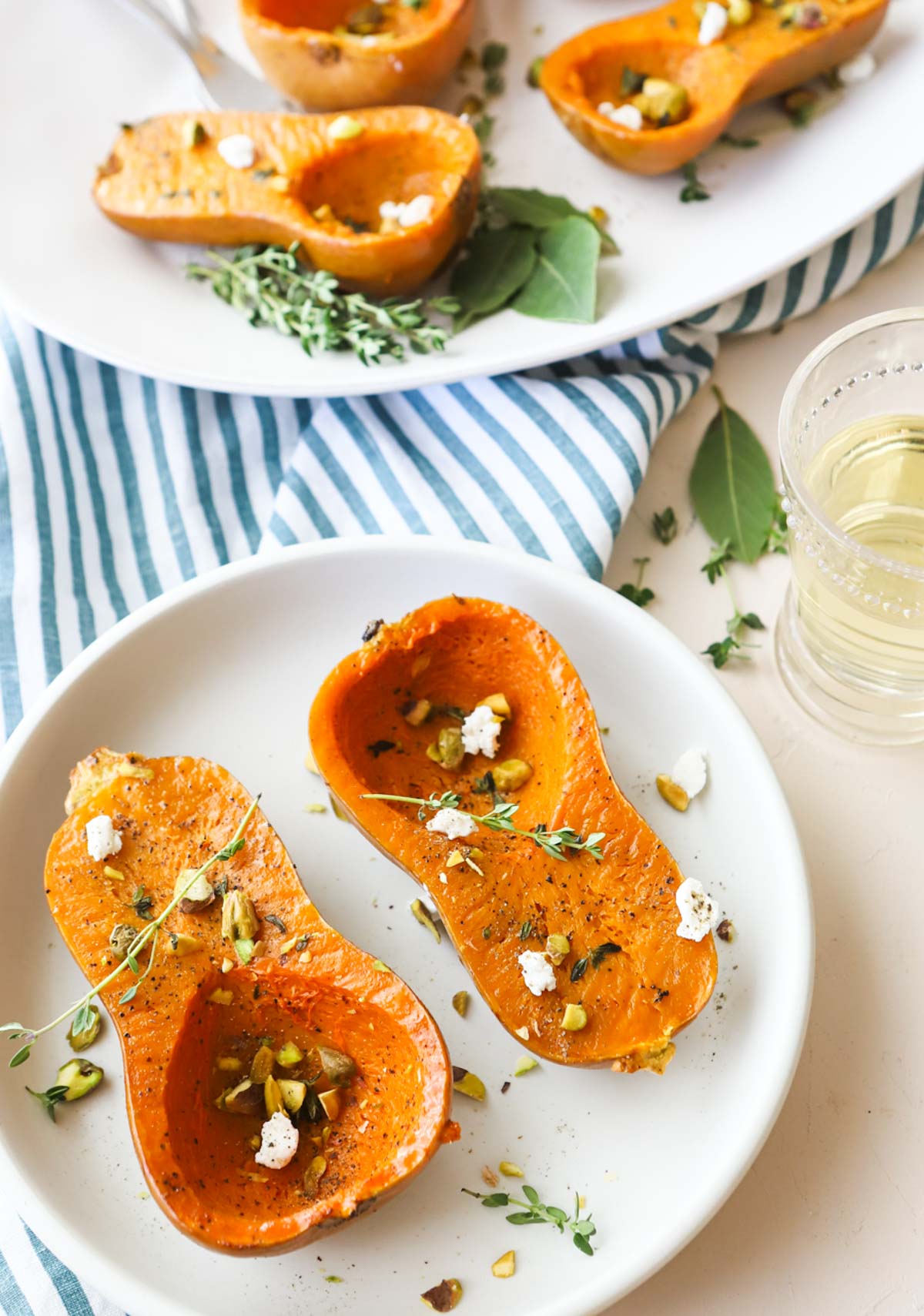 honeynut squash that has been roasted and placed on a white platter and garnished with goat cheese and fresh thyme