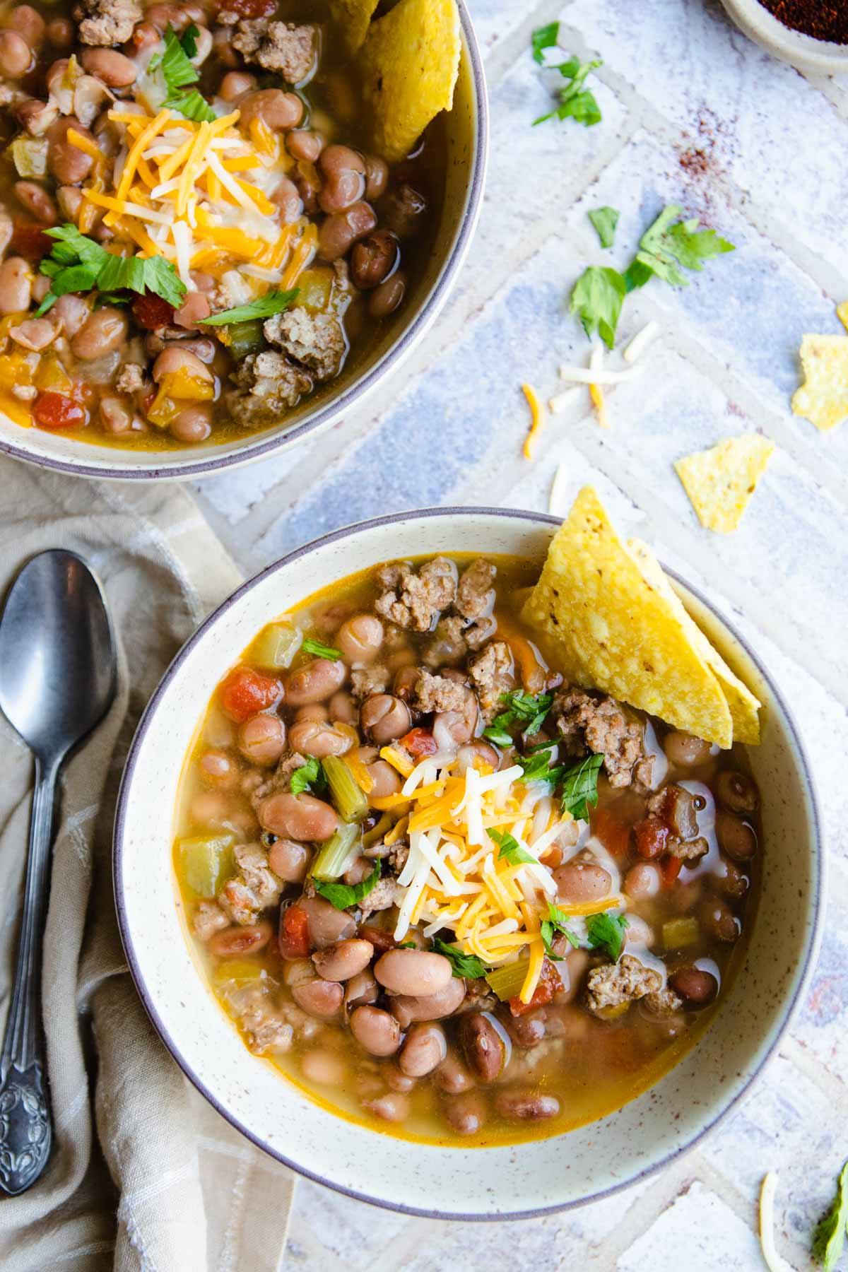 2 bowls of instant pot bean soup garnished with shredded cheese and tortilla chips