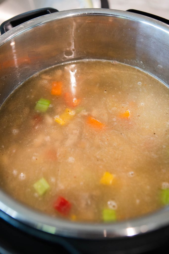 chicken broth and dried beans added to the Instant Pot to make soup