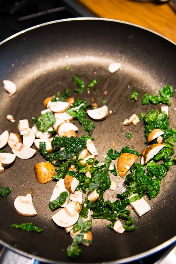 kale and mushrooms cooking in a saute pan