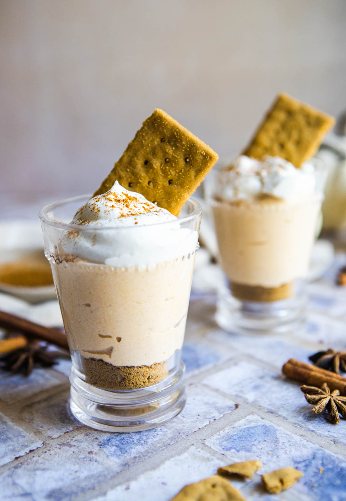 2 glass cups filled with cottage cheese pumpkin fluff and topped with fresh whipped cream and graham crackers 
