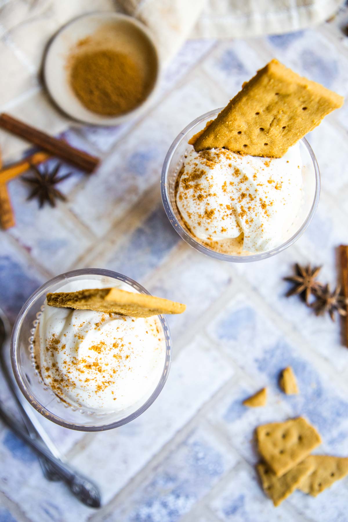 2 glasses filled with pumpkin fluff made with cottage cheese then topped with whipped cream