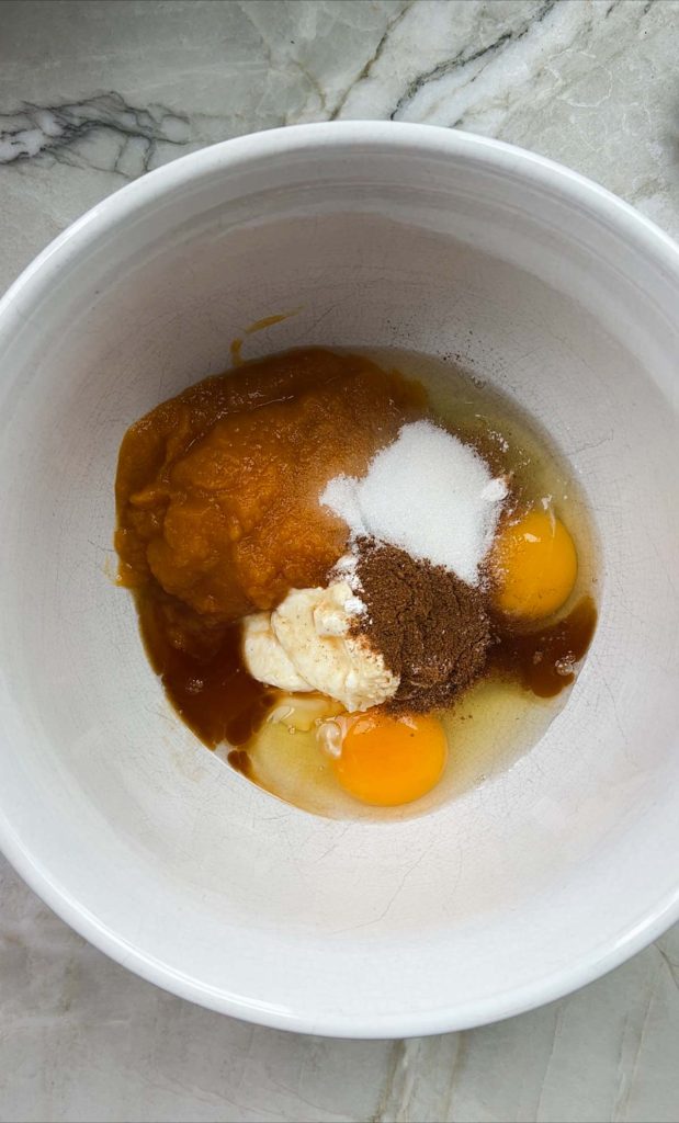 eggs, pumpkin, greek yogurt, vanilla and sugar added to a white mixing bowl