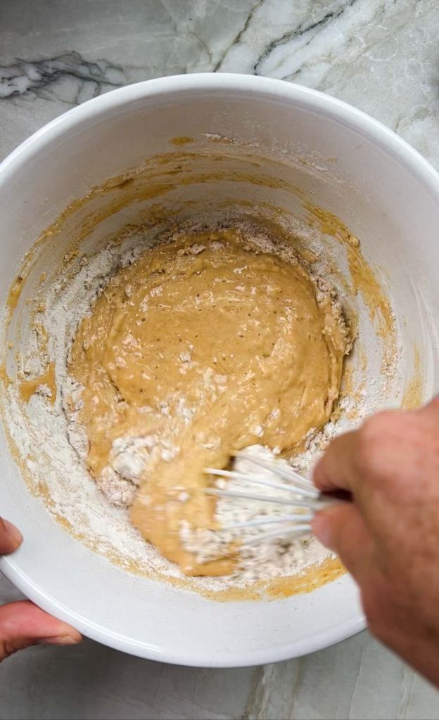 flour being whisked into pumpkin pancake batter