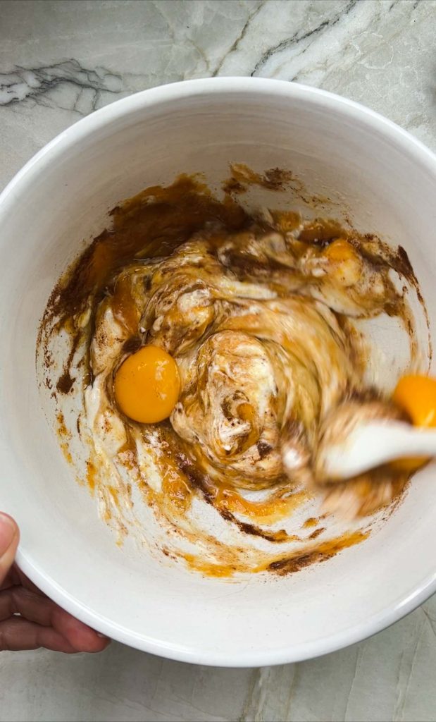 raw ingredients to make pumpkin pancakes being stirred in a white mixing bowl 