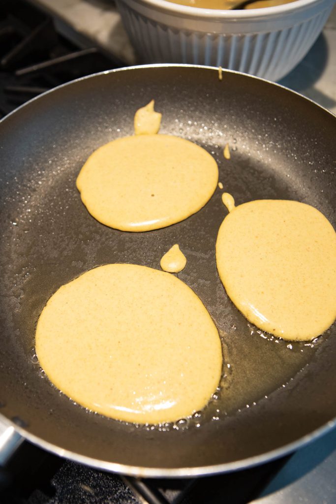 pumpkin pancake batter being cooked in a warm skillet