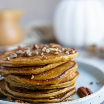 a short stack of protein pumpkin pancakes with syrup poured on top