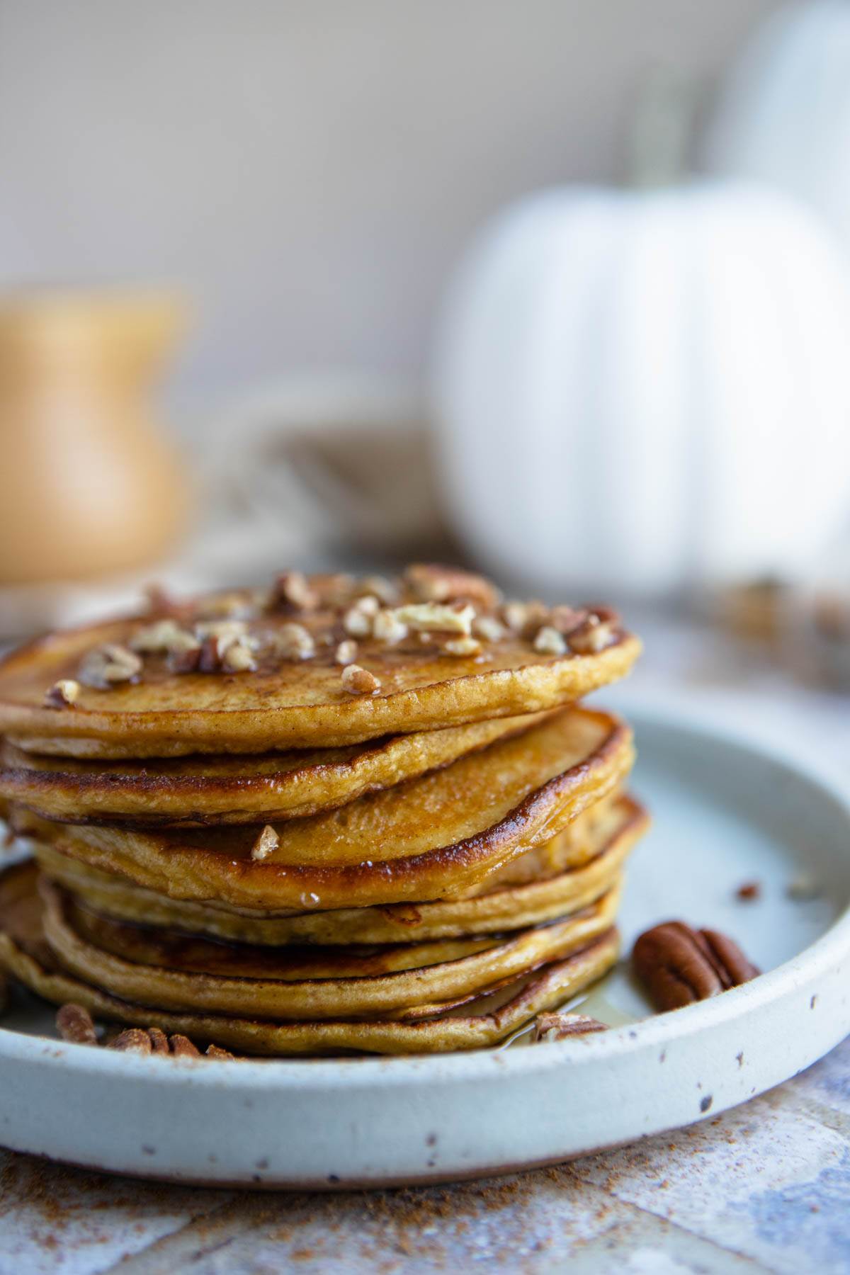 a short stack of protein pumpkin pancakes with syrup poured on top