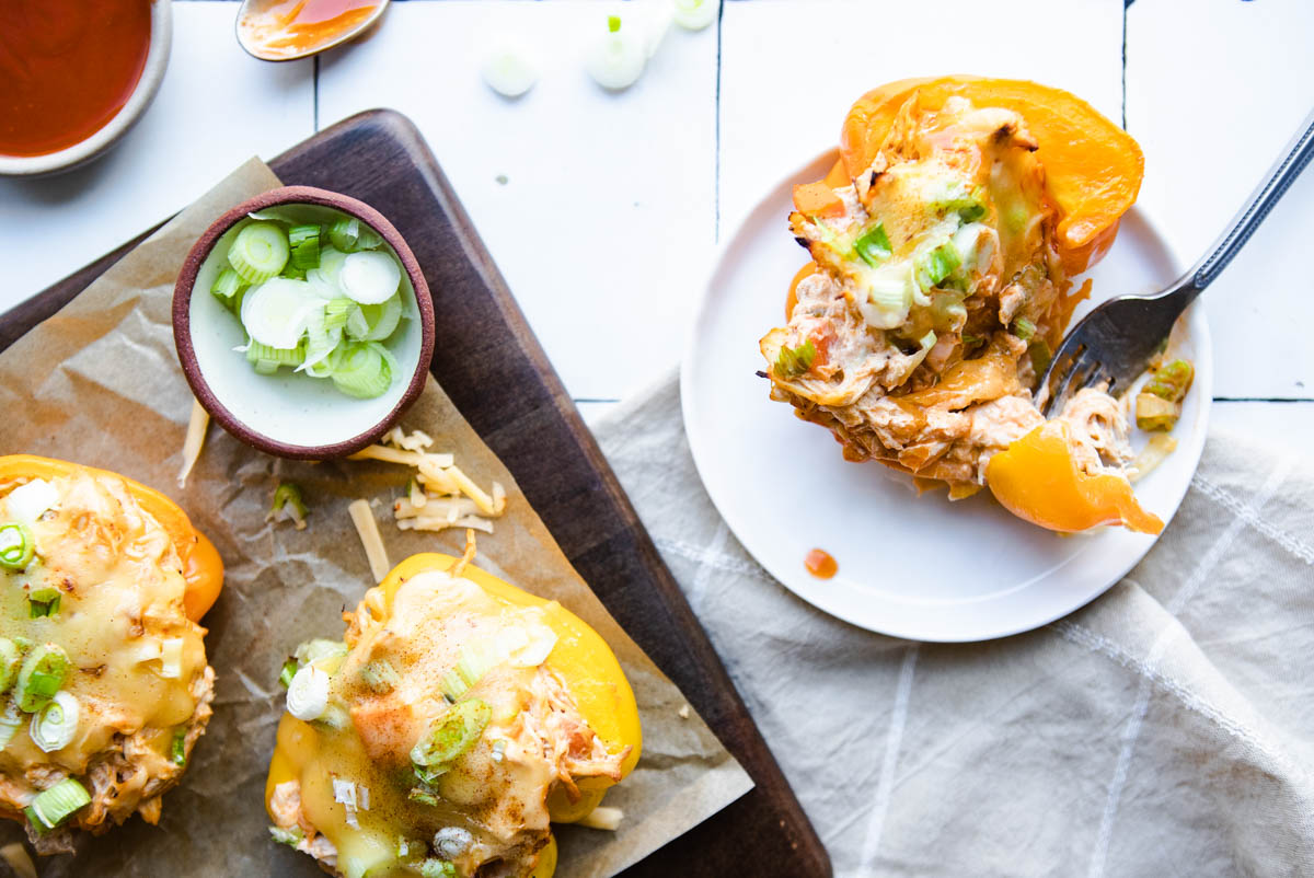 cut open chicken stuffed peppers next to a sheet pan 