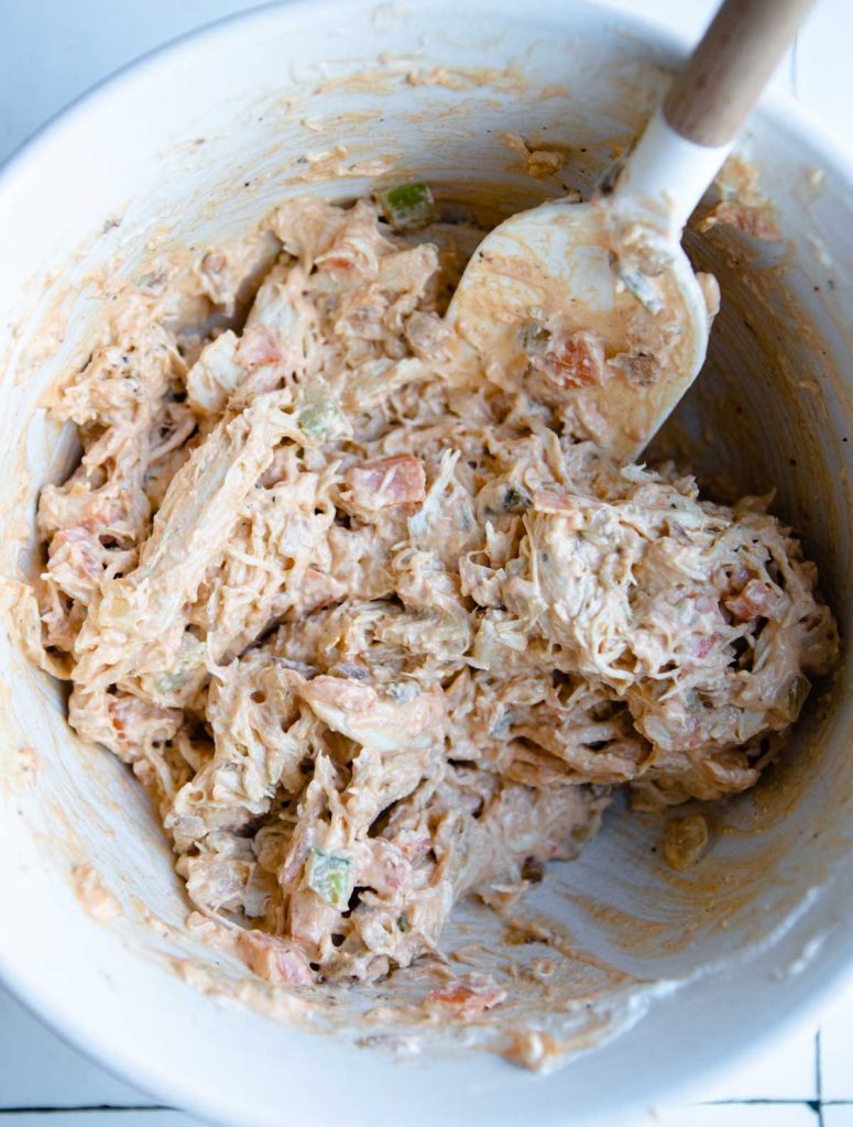 shredded buffalo chicken mix in a white mixing bowl