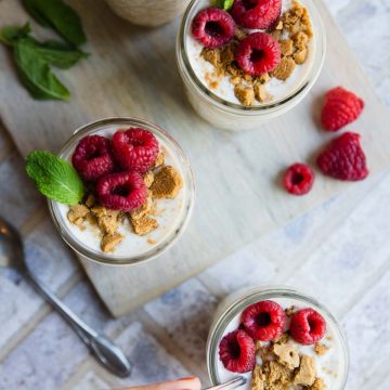 4 small mason jars filled with cheesecake overnight oats and topped with raspberries