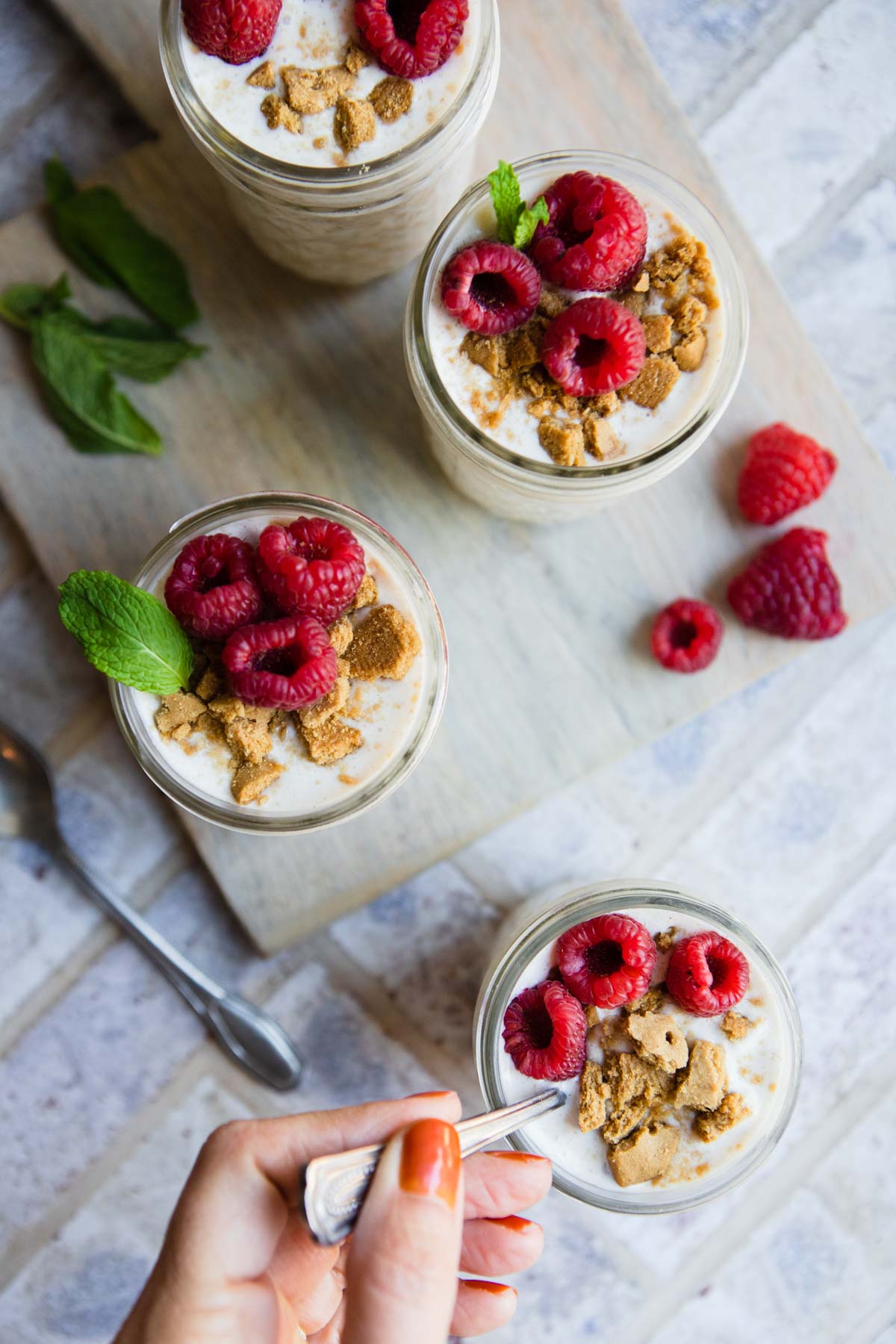 4 small mason jars filled with cheesecake overnight oats and topped with raspberries 