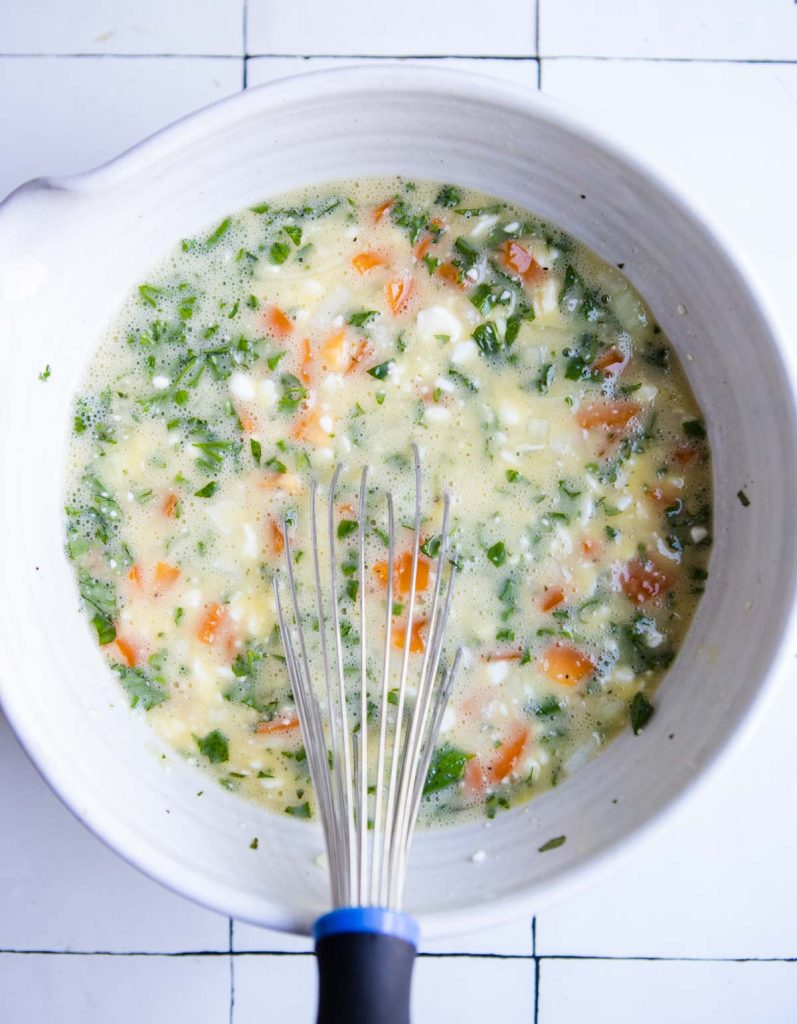 mixed eggs with cottage cheese and fresh veggies ready to pour into a baking dish