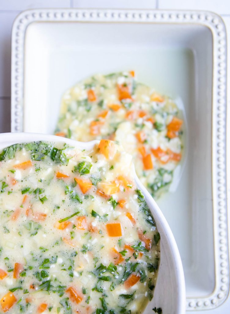 egg and veggie mix being poured into a baking dish