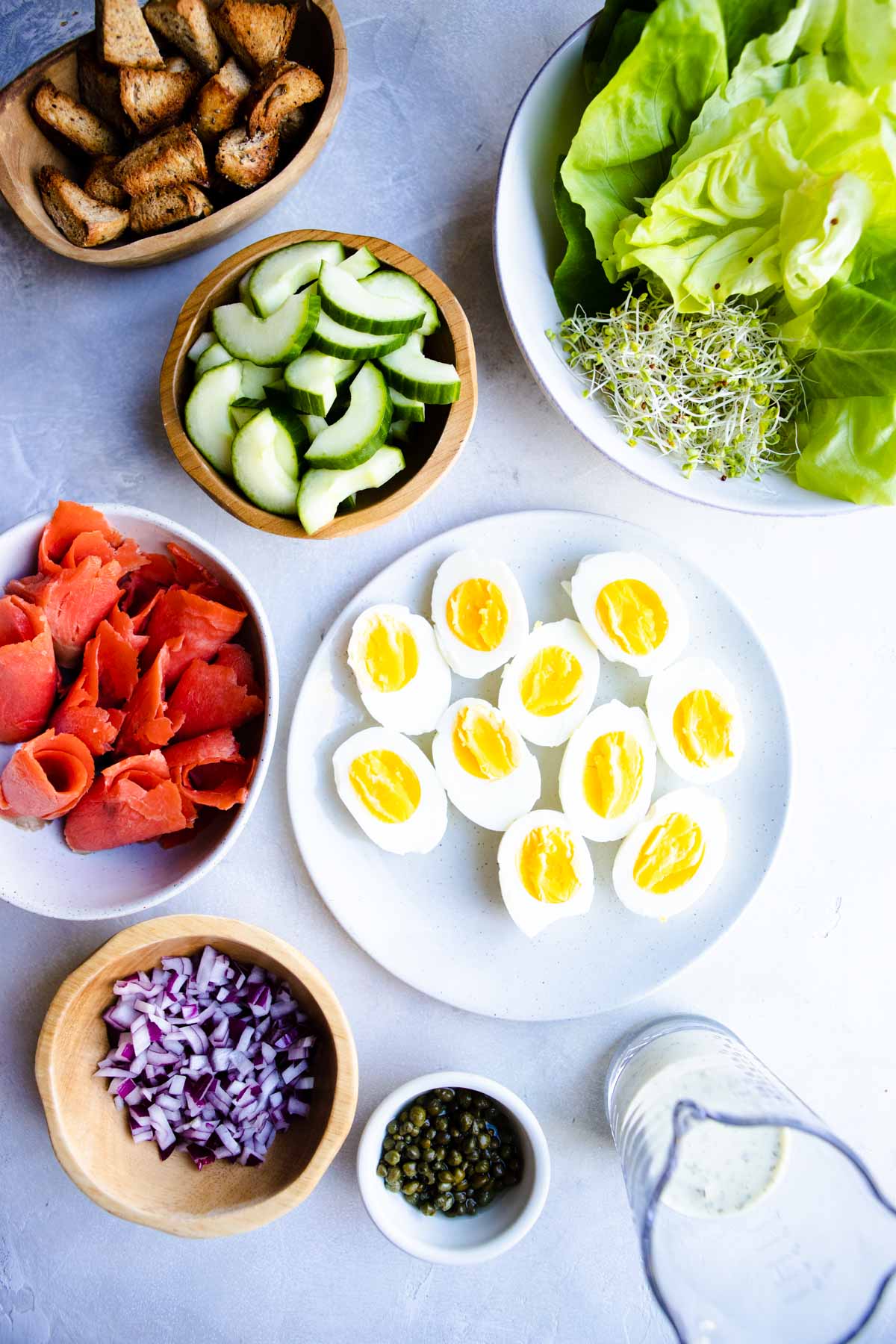 Ingredients to make a smoked salmon breakfast salad set out on a board, ready to be made