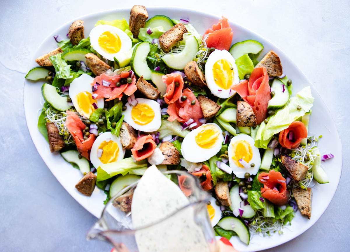 creamy dill dressing being poured onto a salad