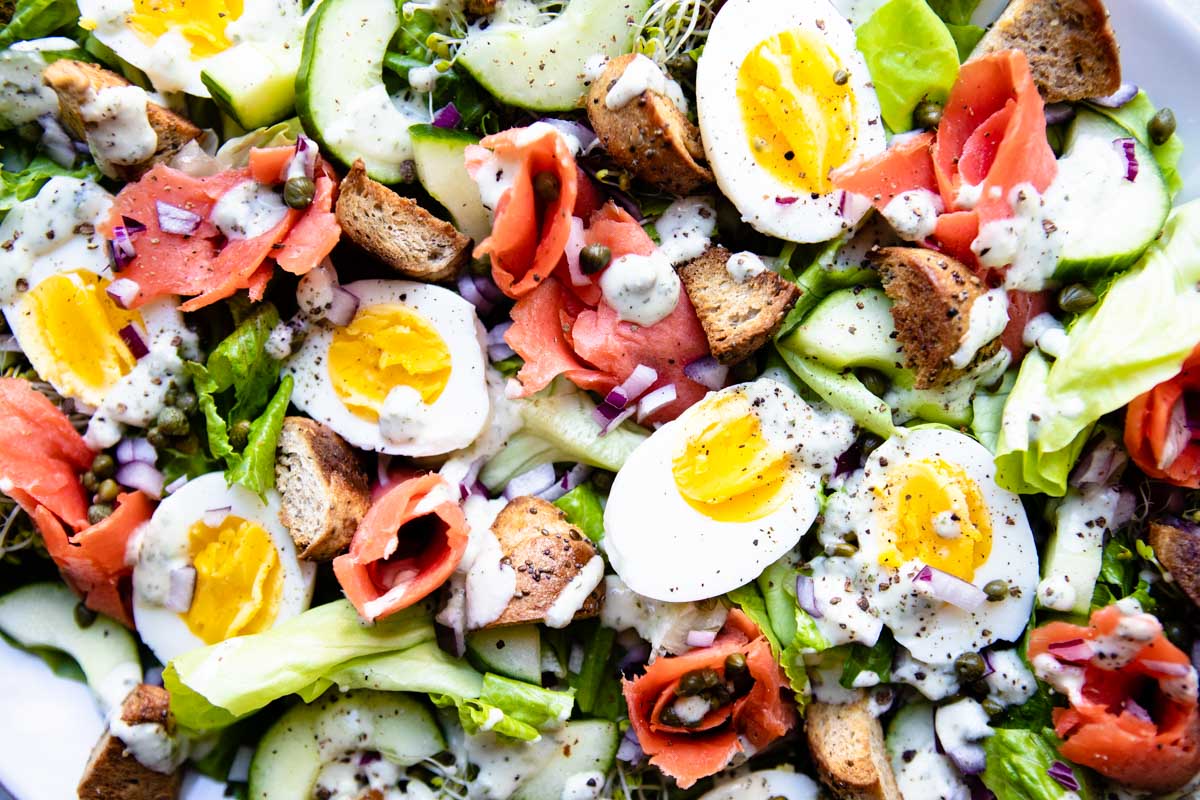 soft-boiled eggs and smoked salmon on a bed of lettuce drizzled with dressing