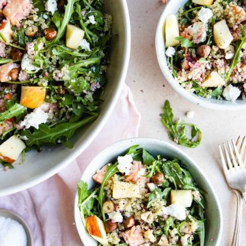 a large salad bowl filled with arugula salad and 2 small bowls filled with salad right next to it