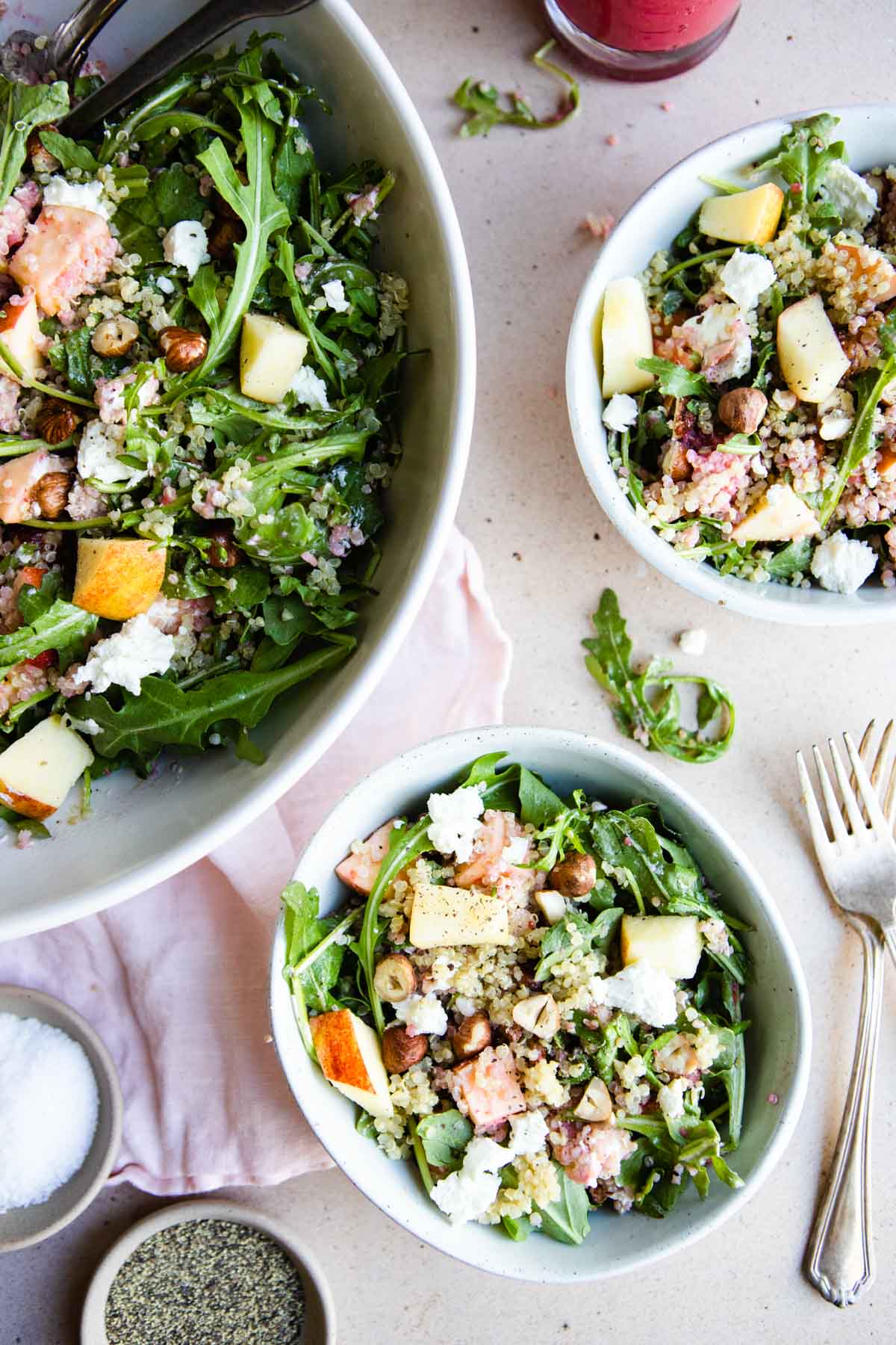 a large salad bowl filled with arugula salad and 2 small bowls filled with salad right next to it