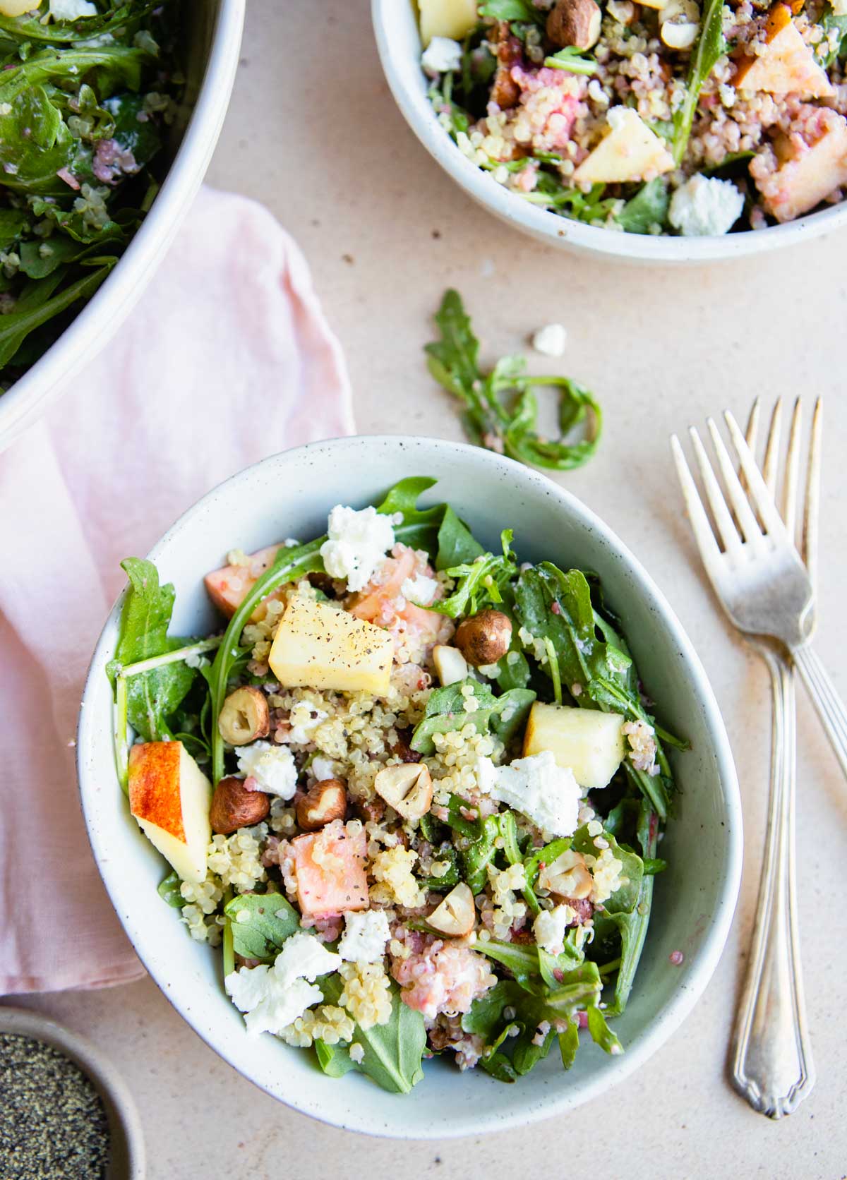 a small round bowl filled with an arugula and quinoa salad