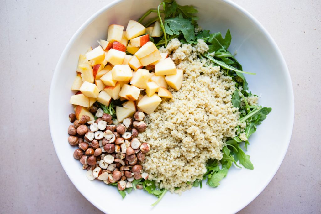 apples, hazelnuts and cooked quinoa on a bed of arugula leaves