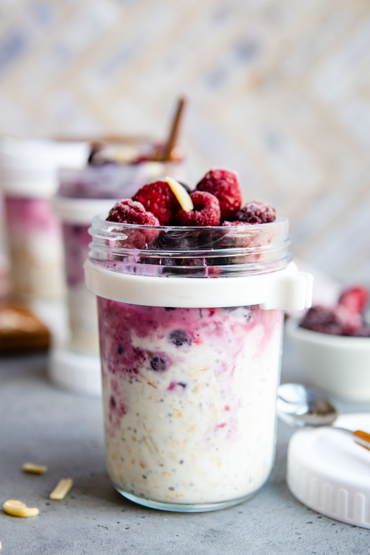 a glass jar filled with overnight oats and frozen berries 