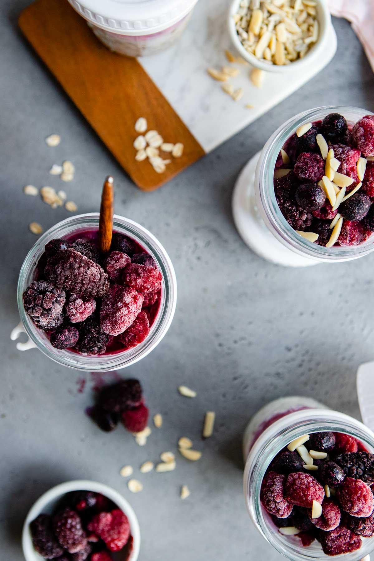 4 glass mason jars filled with overnight oats made with greek yogurt and frozen fruit