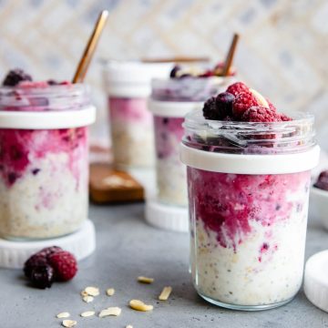 clear glass jars filled with overnight oats with frozen fruit