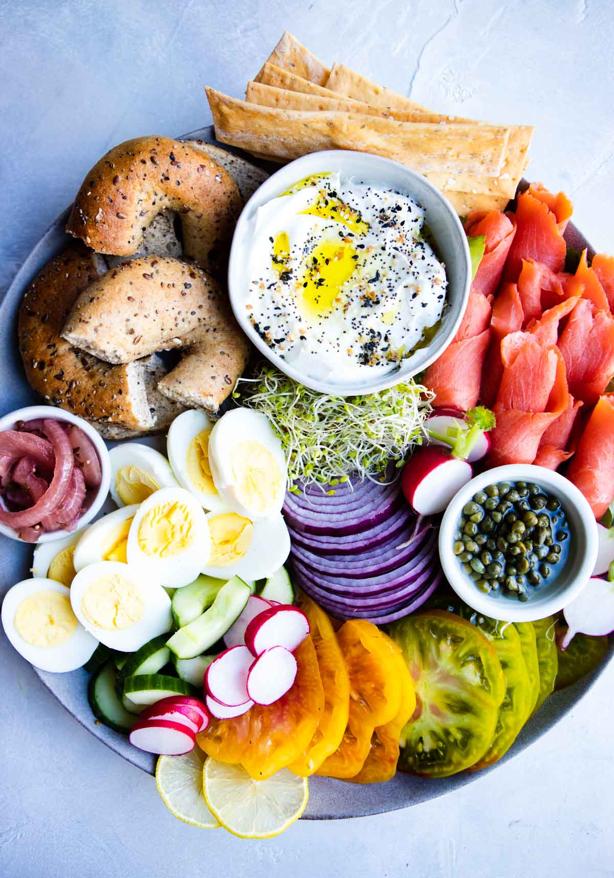 smoked salmon charcuterie board ingredients on a gray platter 