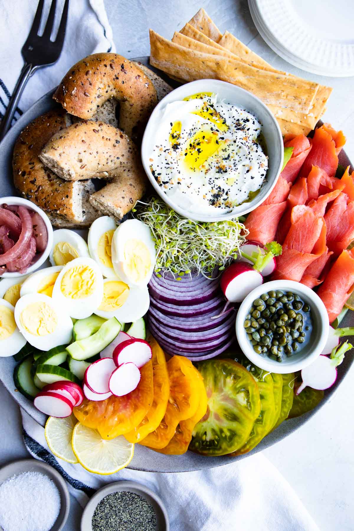 gray platter filled with a smoked salmon charcuterie board and all the garnishes