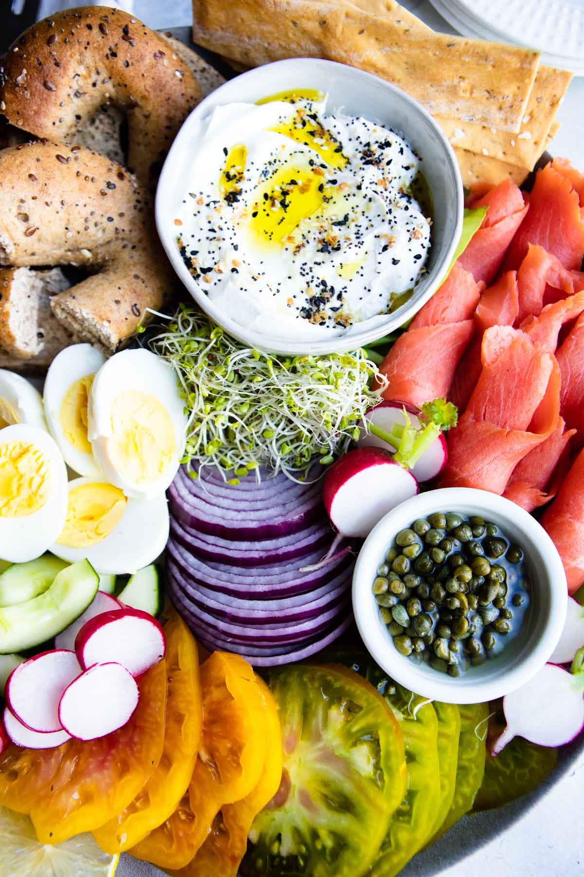 smoked salmon charcuterie board with veggies and hardboiled eggs on a ceramic platter