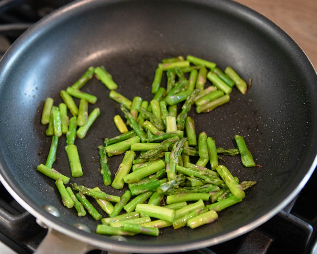 asparagus pieces being cooked in a sauté pan
