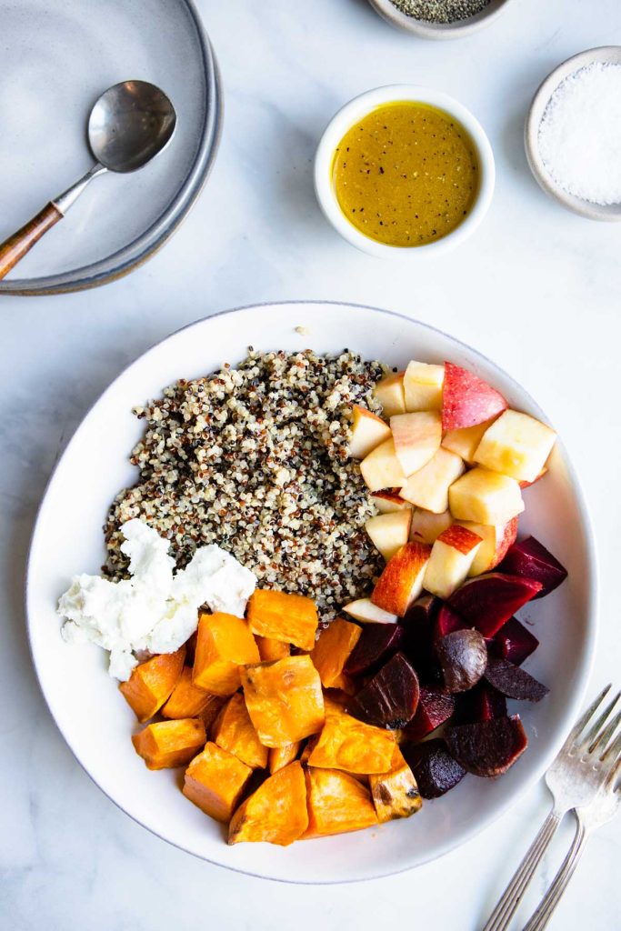 maple vinaigrette ingredients mixed together in a small bowl next to a beet and quinoa salad 