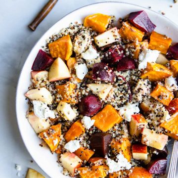 white bowl filled with a quinoa and beet salad with sweet potatoes and goat cheese