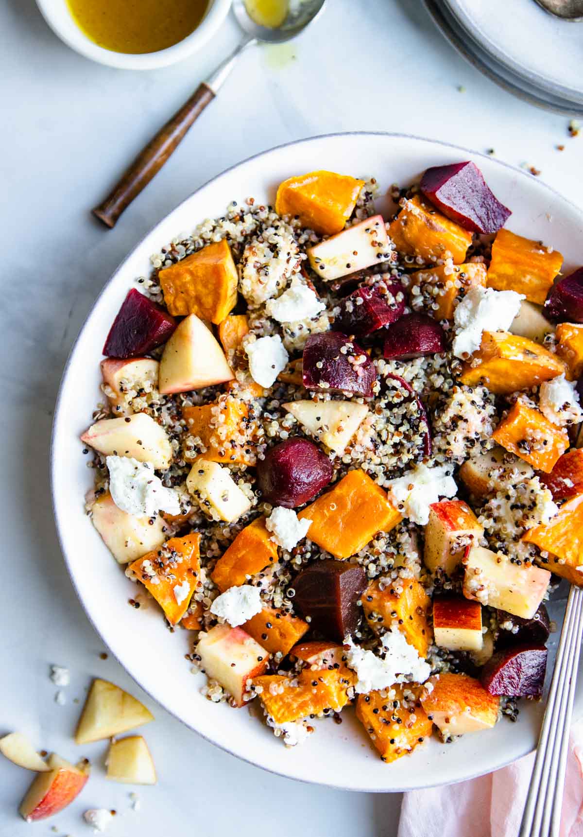 white bowl filled with a quinoa and beet salad with sweet potatoes and goat cheese