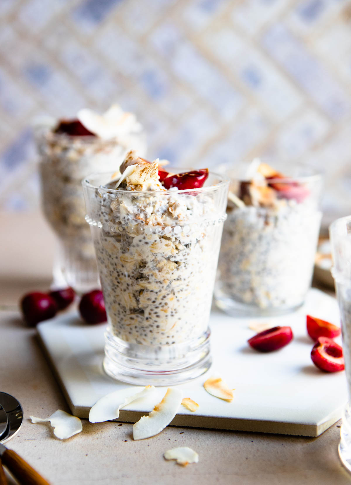 glass drinking cups filled with overnight oats and garnished with fruit