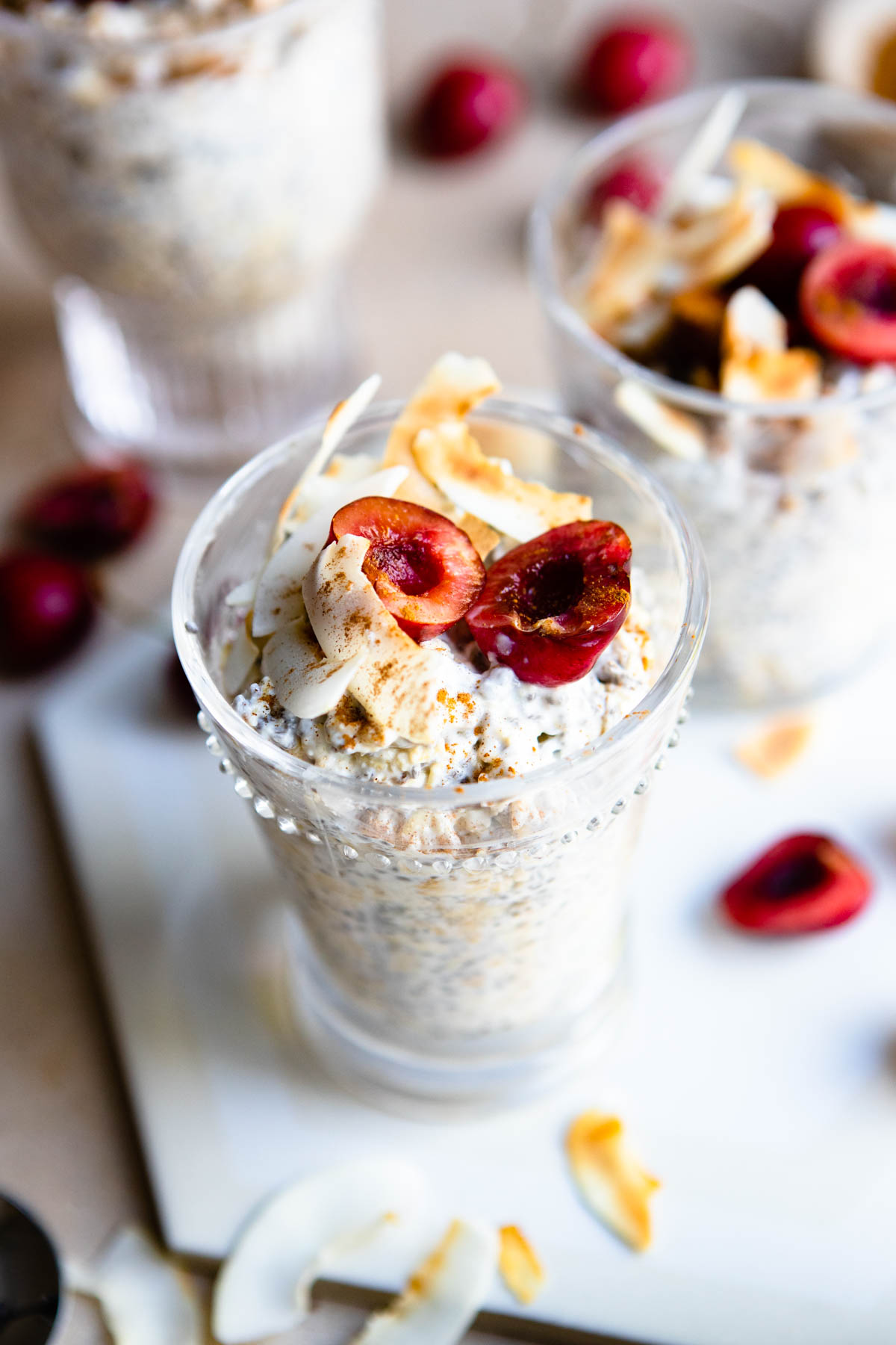 beaded glass cup filled with overnight oats made with kefir, and topped with cherries and toasted coconut flakes