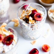 3 glasses filled with kefir overnight oats and topped with coconut flakes and cherries