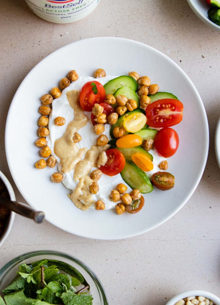 Greek yogurt with sliced veggies, roasted chickpeas and tahini on top