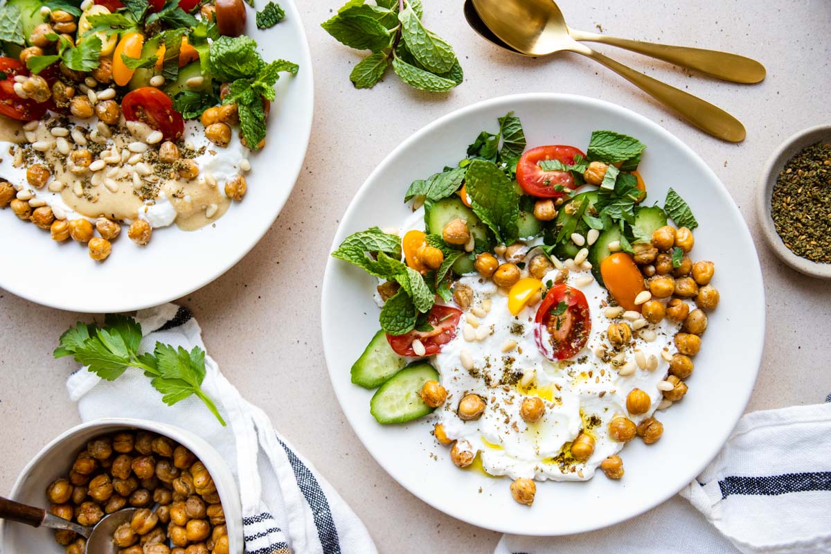 Greek yogurt bowls topped with veggies, herbs and nuts