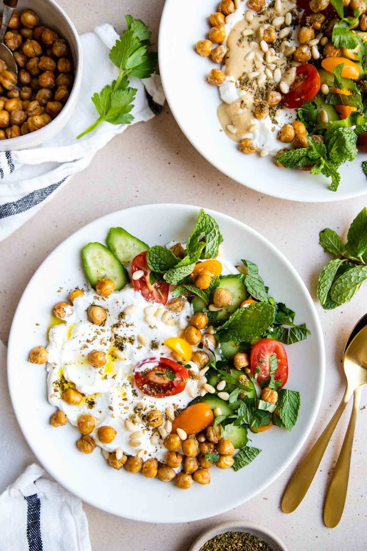 2 white bowls filled with Greek yogurt and savory veggie toppings