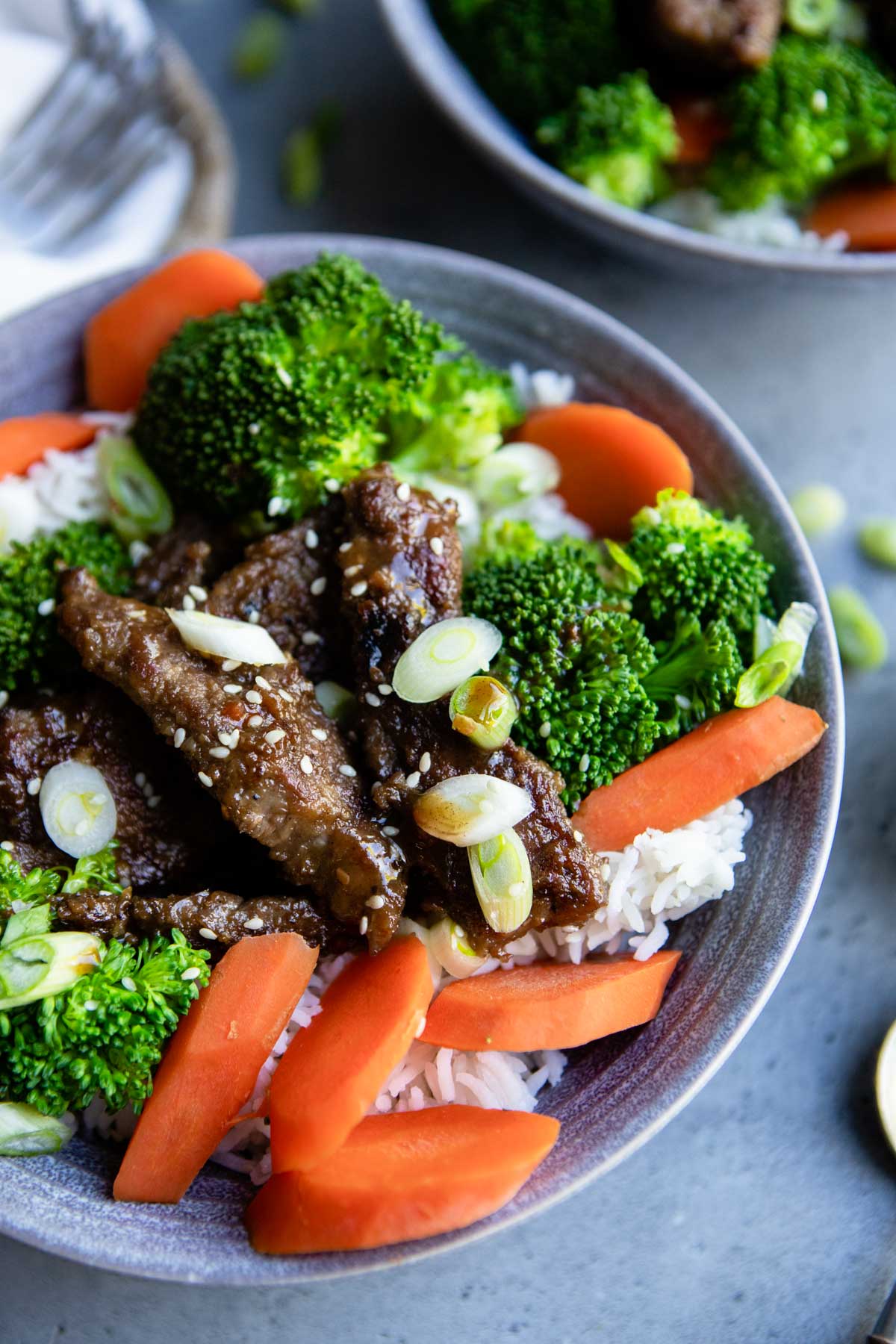 cooked flank steak in a bowl or rice and veggies and drizzled with teriyaki sauce