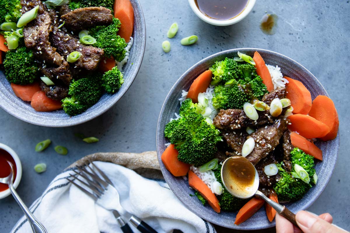 homemade teriyaki sauce being drizzled on beef teriyaki bowls