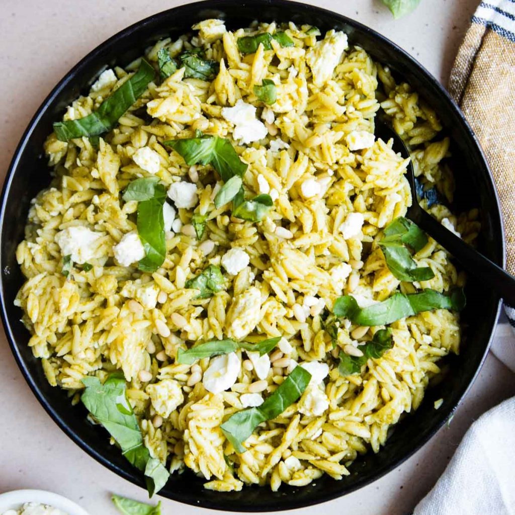orzo pesto salad with crumbled bits of feta and basil garnish