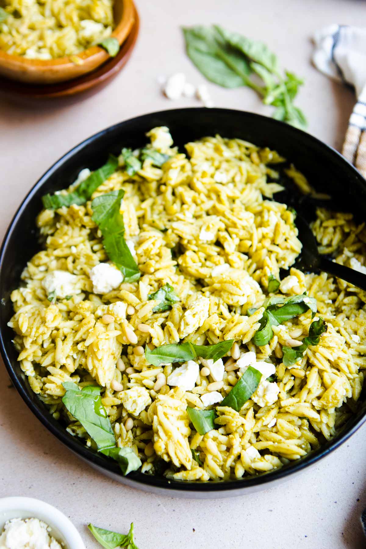 orzo pesto salad being spooned into a serving bowl