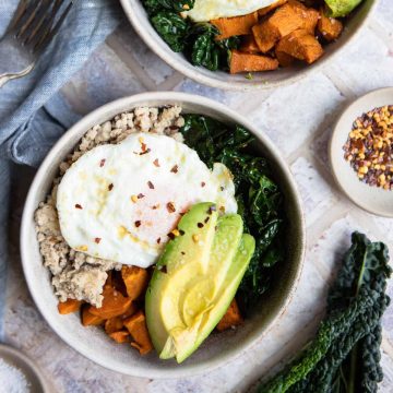 a beige bowl filled with a sweet potato and egg and ground turkey and kale