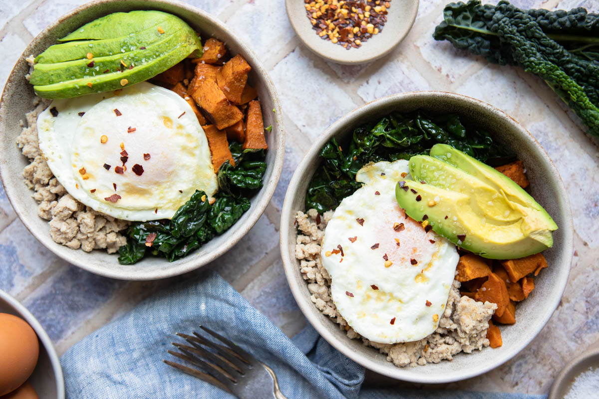 sweet potato breakfast bowls topped with an over easy egg and avocado 
