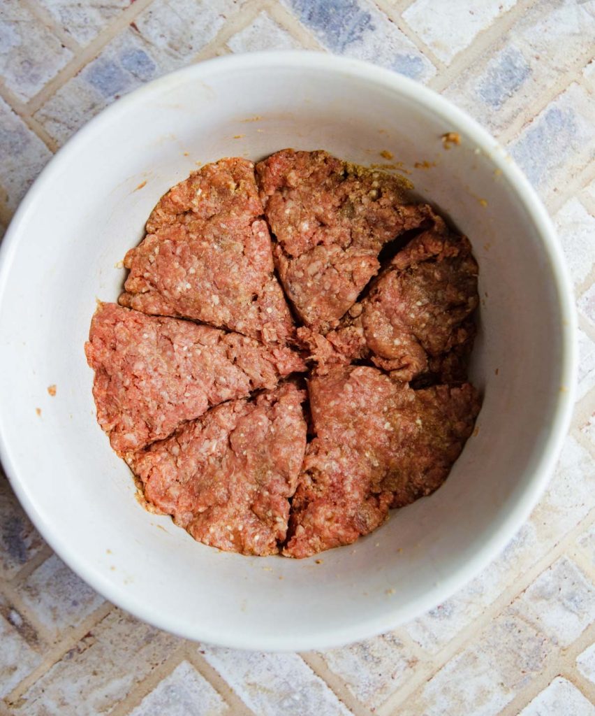 ground beef burger mix in a white bowl divided up into 6 parts to make burger patties