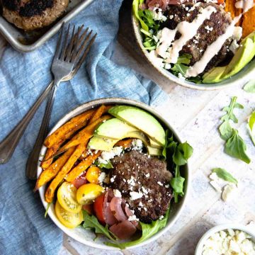 hamburger bowls in a round beige bowl garnished with avocadoes and feta cheese